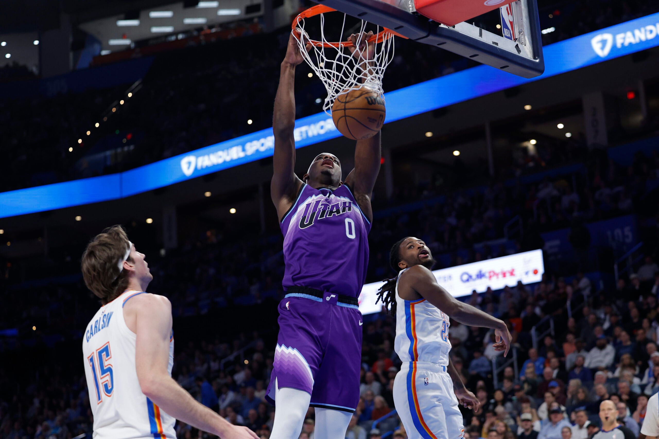 Jan 7, 2026; Oklahoma City, Oklahoma, USA; Utah Jazz forward Taylor Hendricks (0) dunks between Oklahoma City Thunder center Branden Carlson (15) and guard Cason Wallace (22) during the second half at Paycom Center. Mandatory Credit: Alonzo Adams-Imagn Images