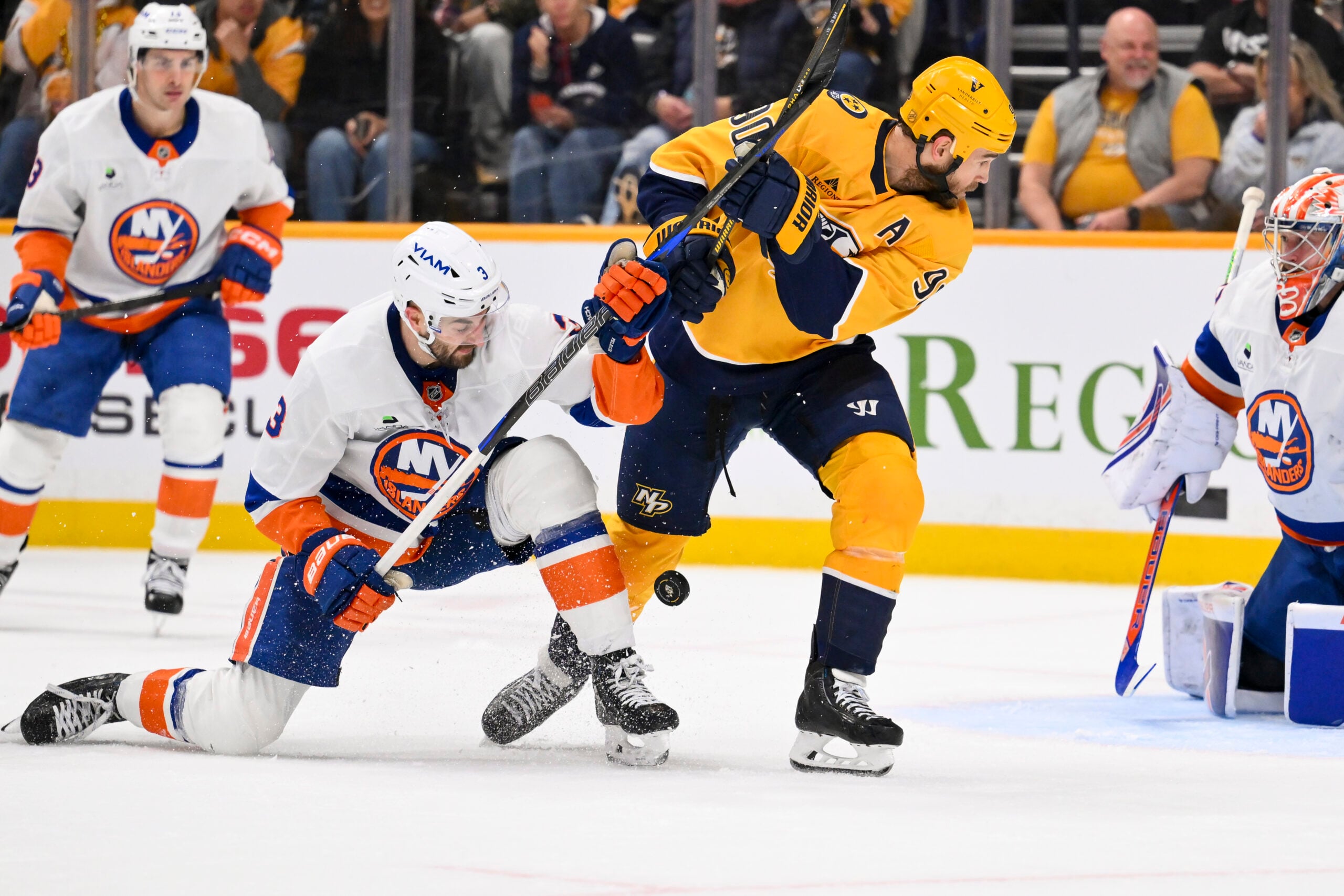 Jan 8, 2026; Nashville, Tennessee, USA; Nashville Predators center Ryan O'Reilly (90) and New York Islanders defenseman Adam Pelech (3) battle for the puck during the third period at Bridgestone Arena. Mandatory Credit: Steve Roberts-Imagn Images