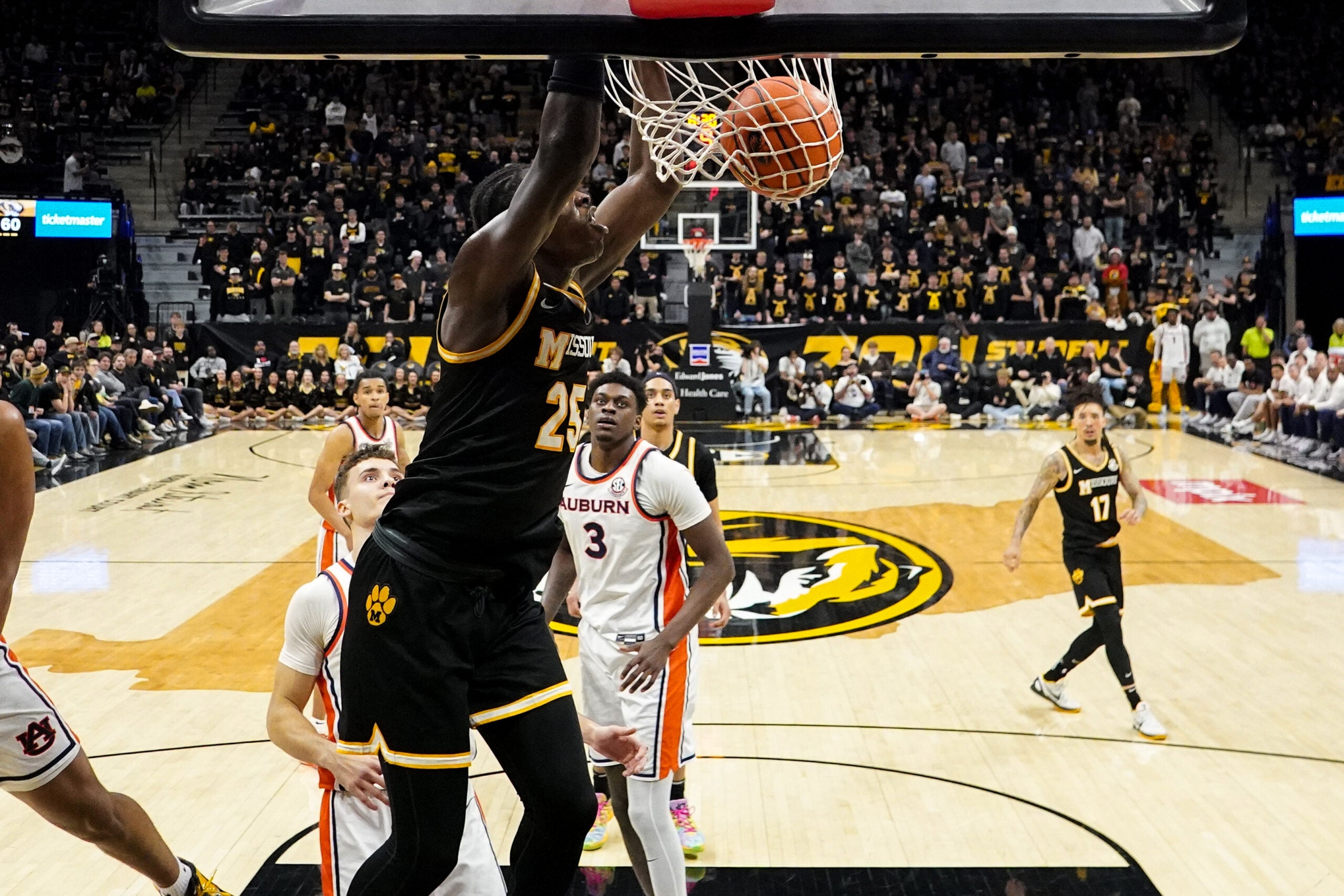 Jan 14, 2026; Columbia, Missouri, USA; Missouri Tigers guard Mark Mitchell (25) dunks he ball as Auburn Tigers forward Keshawn Murphy (3) looks on during the second half of the game at Mizzou Arena. Mandatory Credit: Denny Medley-Imagn Images