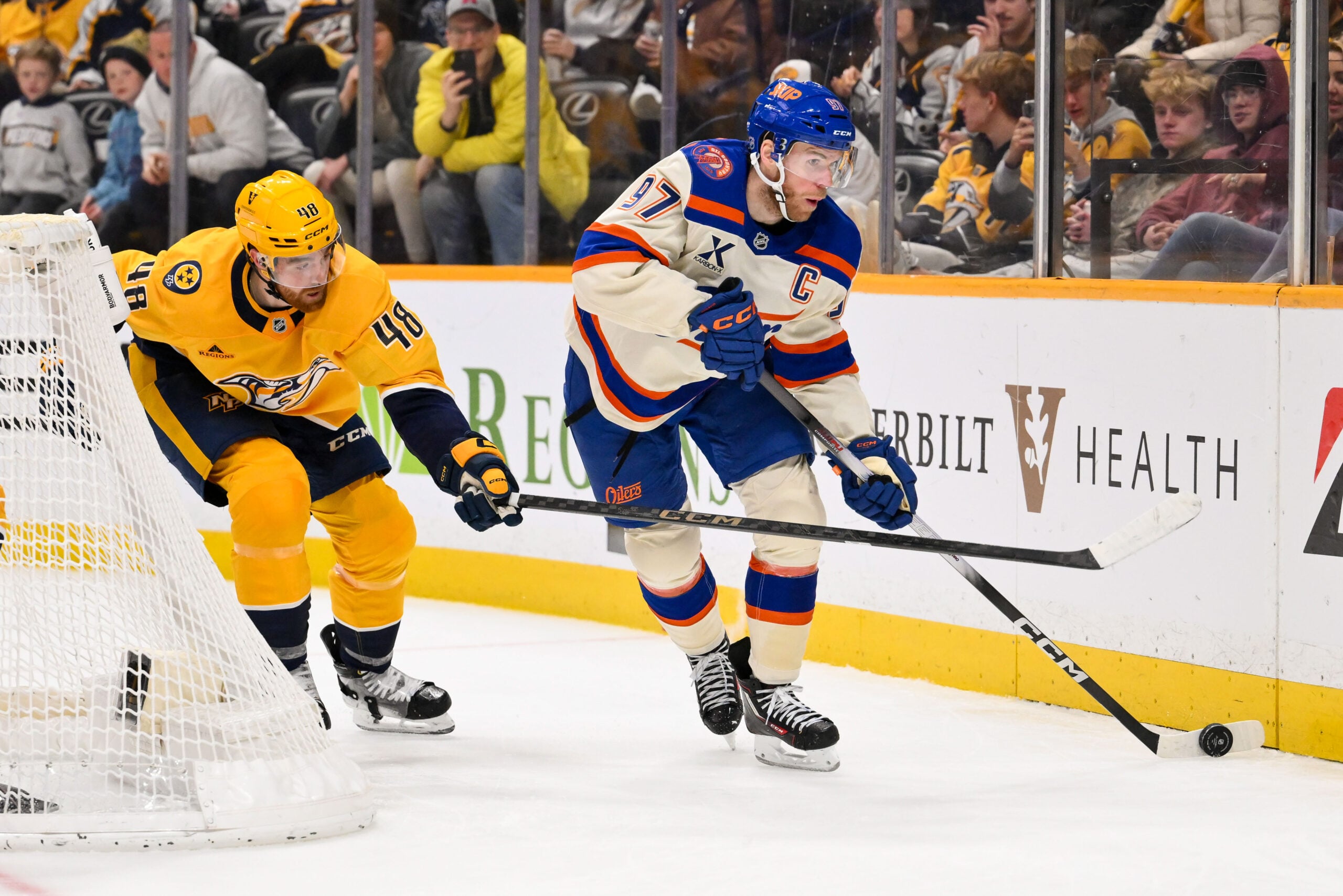 Jan 13, 2026; Nashville, Tennessee, USA;  Nashville Predators defenseman Nick Perbix (48) pokes at the puck as Edmonton Oilers center Connor McDavid (97) skates during the second period at Bridgestone Arena. Mandatory Credit: Steve Roberts-Imagn Images