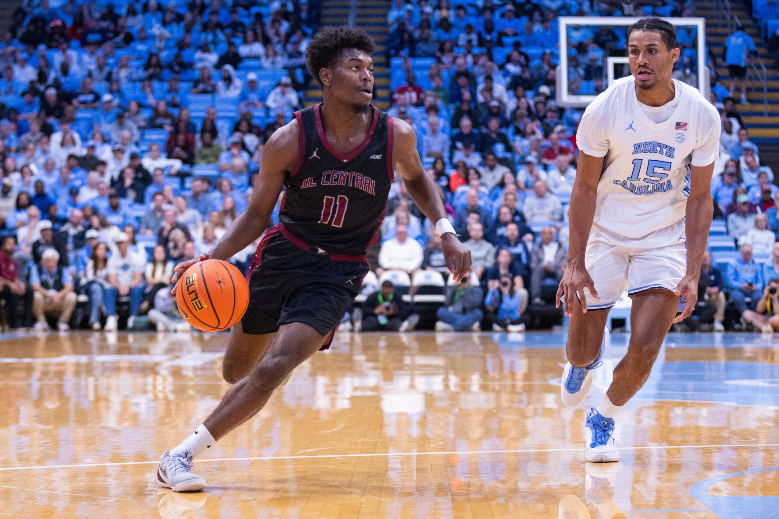 Nov 14, 2025; Chapel Hill, North Carolina, USA; North Carolina Central Eagles guard Gage Lattimore (11) drives past North Carolina Tar Heels forward Jarin Stevenson (15) during the first half at Dean E. Smith Center. Mandatory Credit: Scott Kinser-Imagn Images