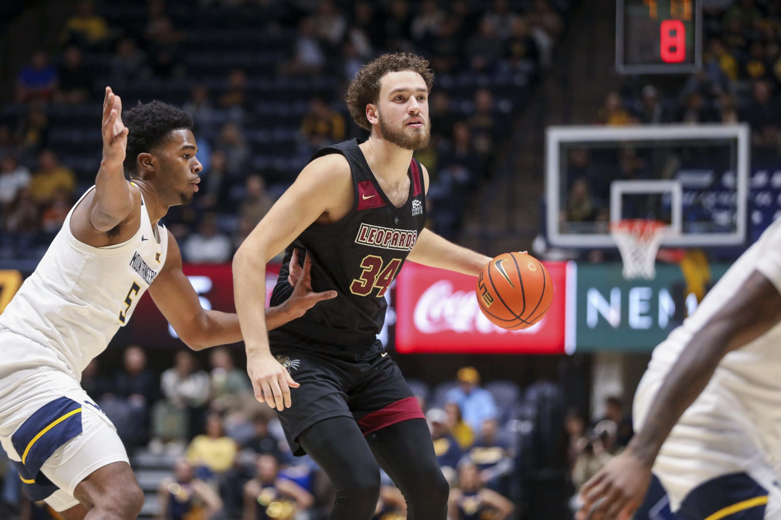 Nov 17, 2025; Morgantown, West Virginia, USA; Lafayette Leopards forward Luke Bevilacqua (34) dribbles against West Virginia Mountaineers forward DJ Thomas (5) during the first half at WVU Coliseum. Mandatory Credit: Ben Queen-Imagn Images