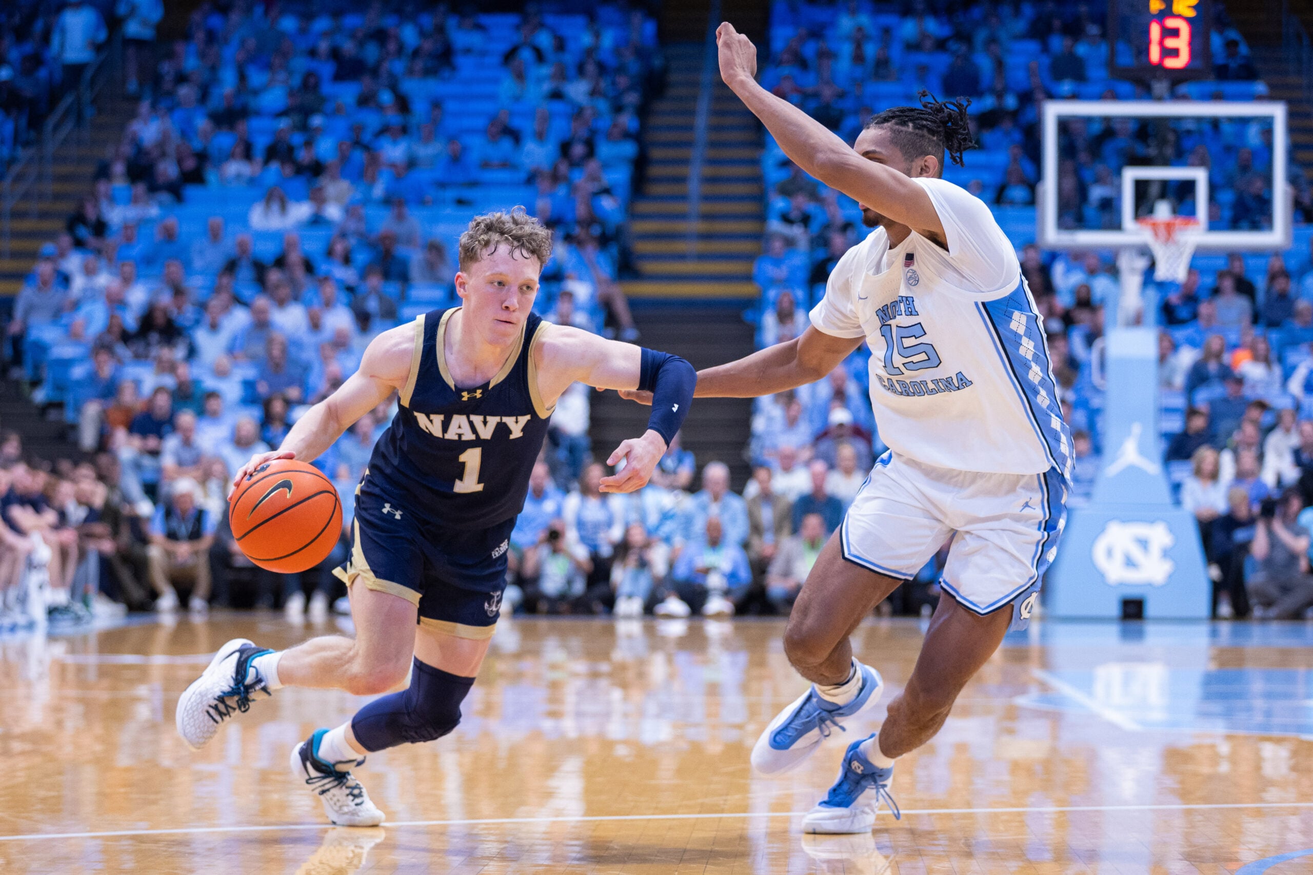 Nov 18, 2025; Chapel Hill, North Carolina, USA; Navy Midshipmen guard Austin Benigni (1) drives on North Carolina Tar Heels forward Jarin Stevenson (15) during the first half at Dean E. Smith Center. Mandatory Credit: Scott Kinser-Imagn Images