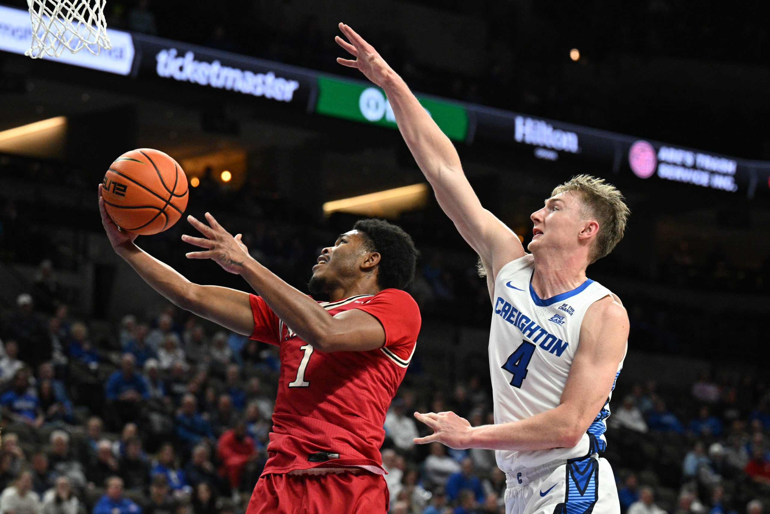 Dec 2, 2025; Omaha, Nebraska, USA;  Nicholls State Colonels guard Trae English (1) scores against Creighton Bluejays guard Josh Dix (4) during the first half at CHI Health Center Omaha. Mandatory Credit: Steven Branscombe-Imagn Images