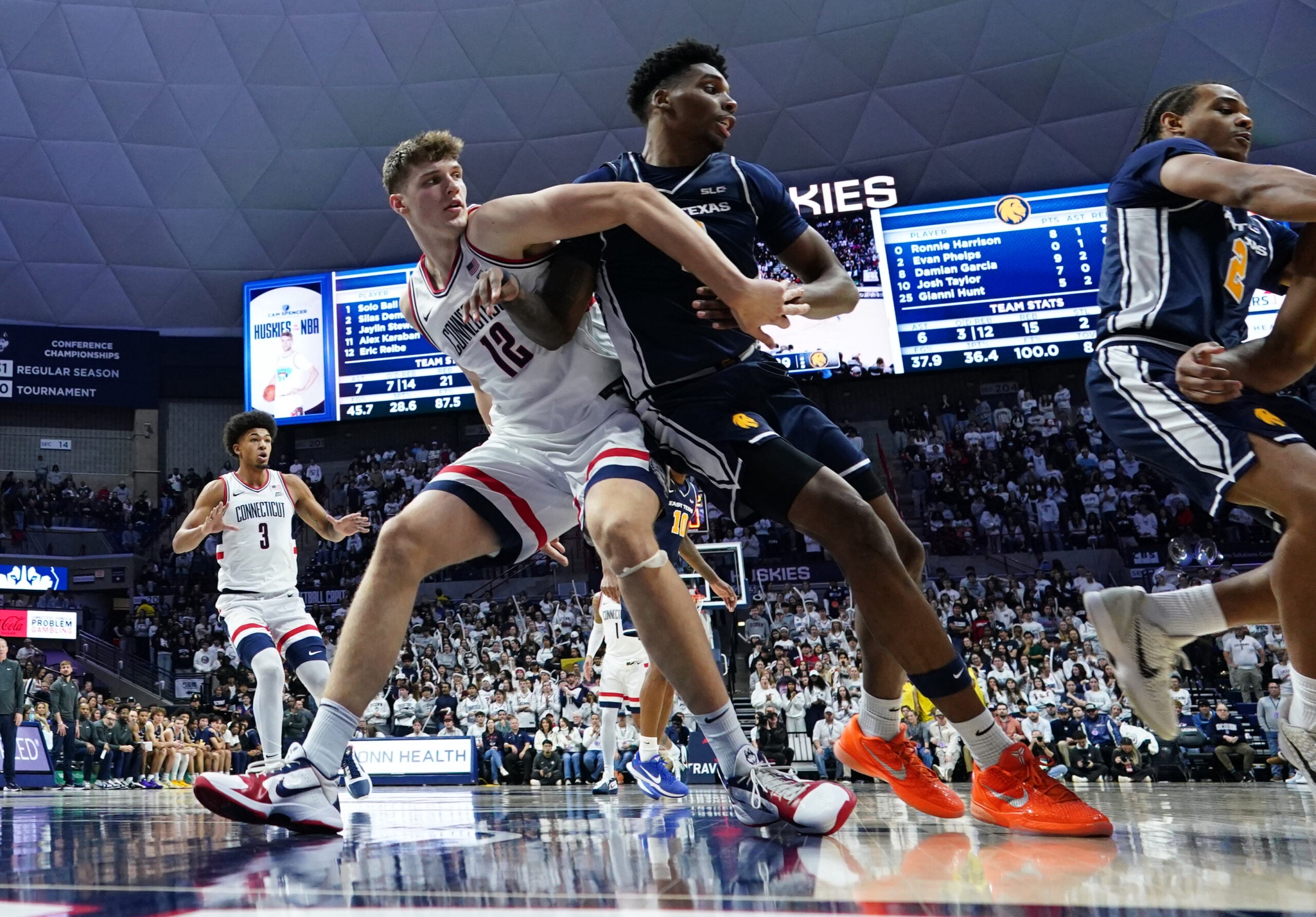 Dec 5, 2025; Storrs, Connecticut, USA; UConn Huskies center Eric Reibe (12) defends against East Texas A&M Lions forward Ronnie Harrison (0) in the second half at Harry A. Gampel Pavilion. Mandatory Credit: David Butler II-Imagn Images
