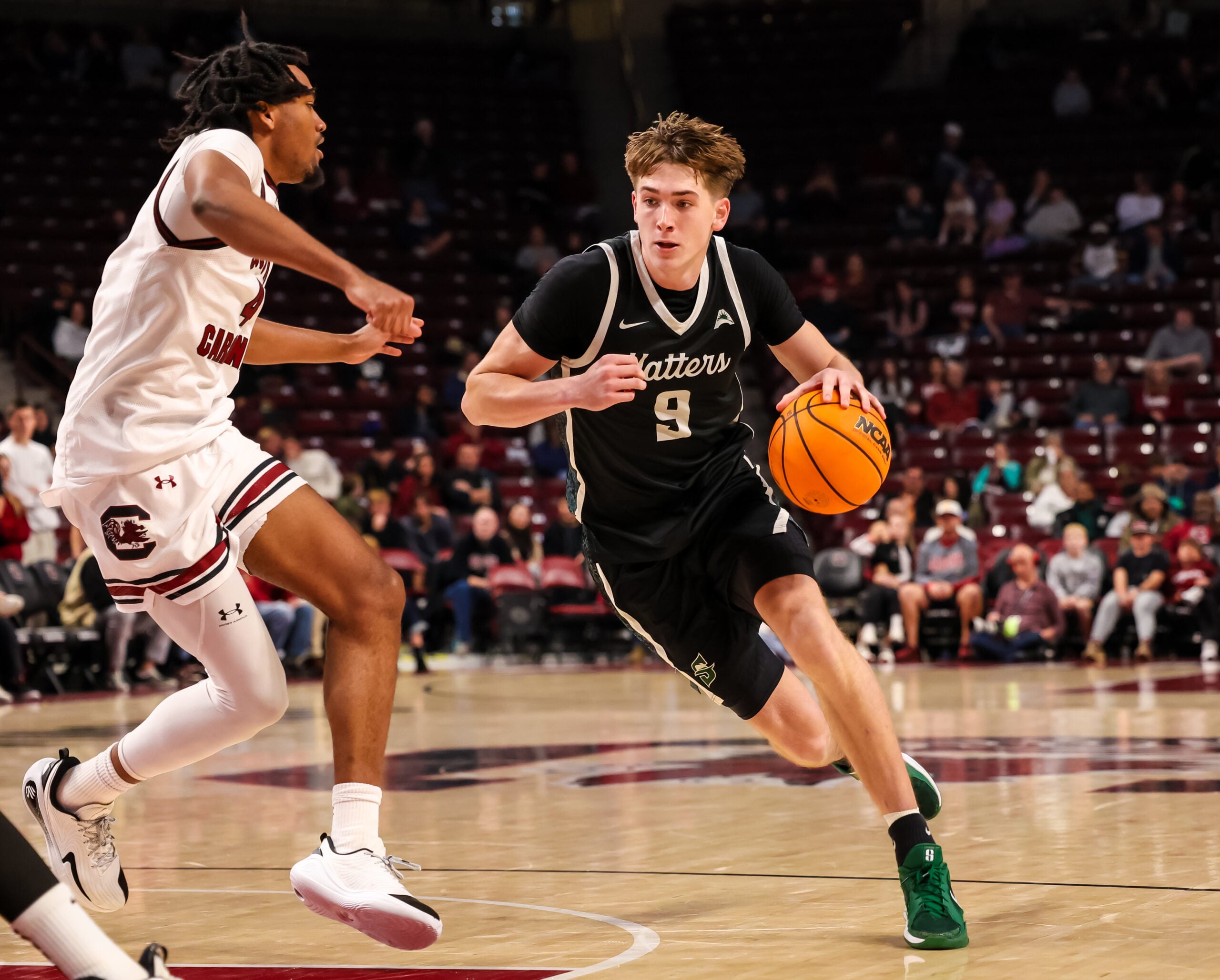 Dec 6, 2025; Columbia, South Carolina, USA; Stetson Hatters forward Collin Kuhl (9) drives past South Carolina Gamecocks guard Kobe Knox (4) in the second half at Colonial Life Arena. Mandatory Credit: Jeff Blake-Imagn Images