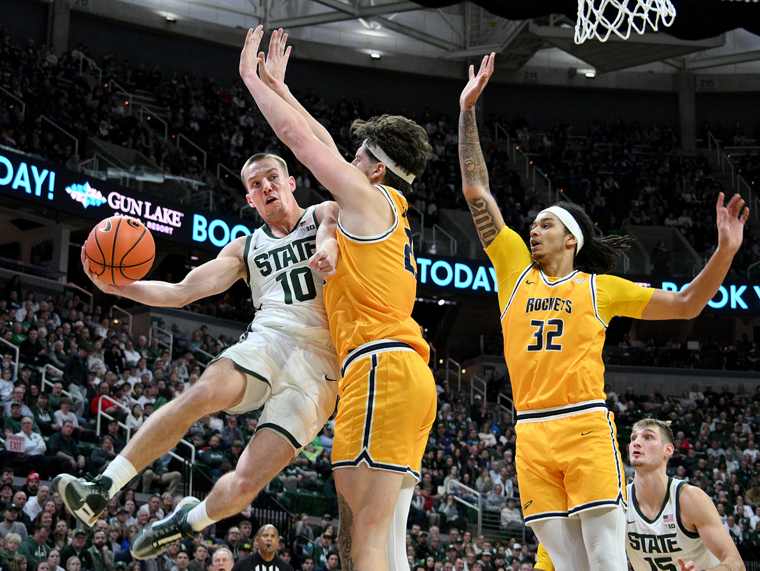 Dec 16, 2025; East Lansing, Michigan, USA; Michigan State Spartans guard Denham Wojcik (10) passes the ball around Toledo Rockets center Austin Parks (25) during the second half at Jack Breslin Student Events Center. Mandatory Credit: Dale Young-Imagn Images