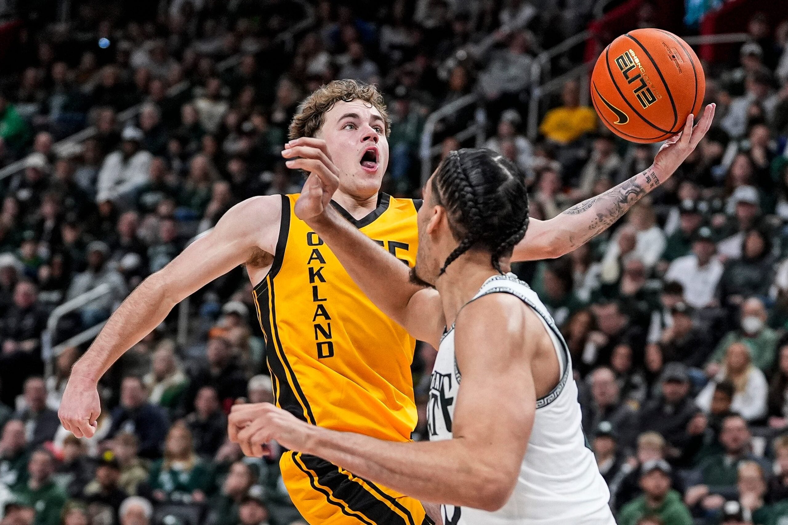 Oakland guard Brody Robinson (55) makes a layup against Michigan State forward Jesse McCulloch (35) during the first half at Little Caesars Arena in Detroit on Saturday, Dec. 20, 2025.