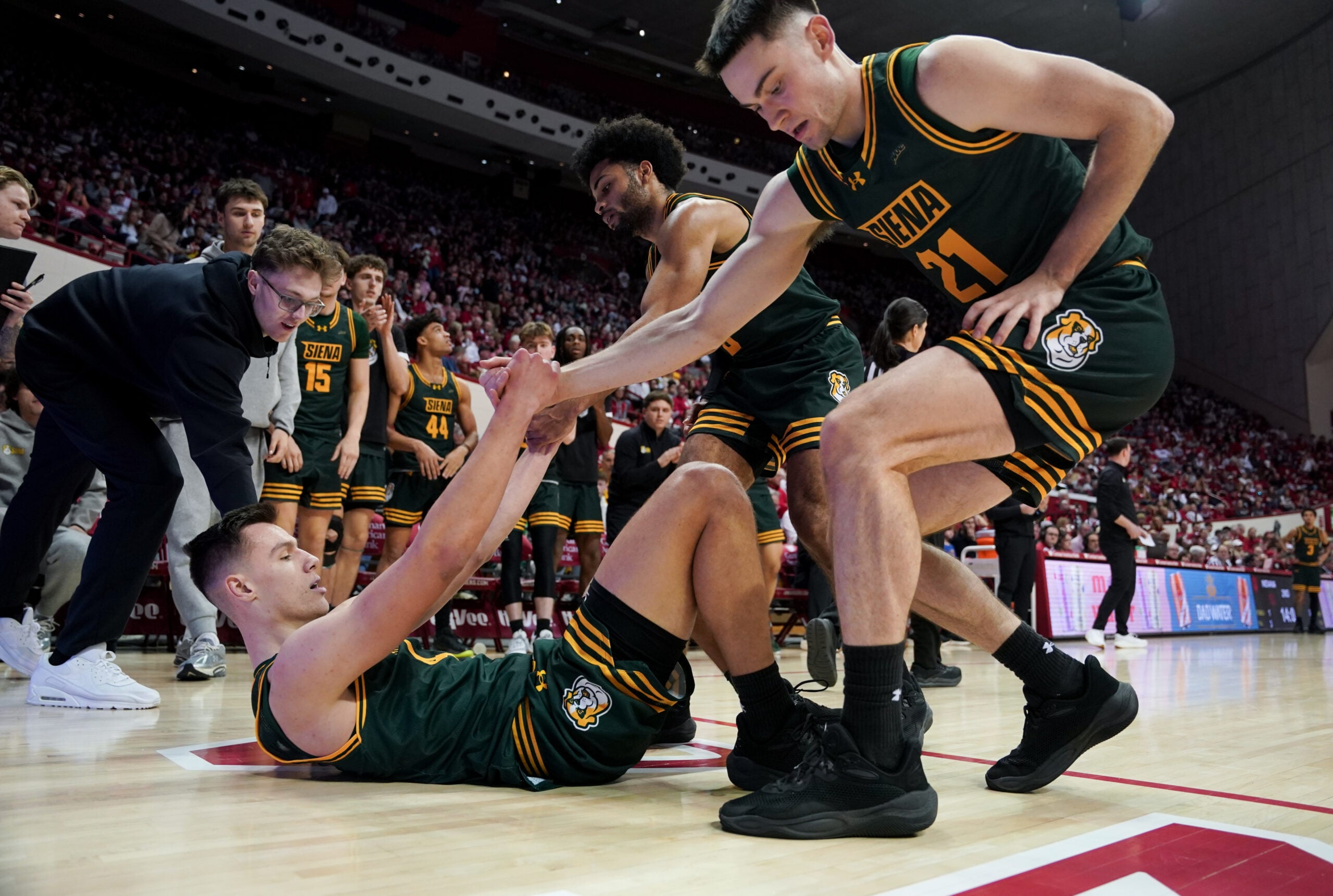 Dec 22, 2025; Bloomington, Indiana, USA; Siena Saints forward Brendan Coyle (21) and Siena Saints guard Justice Shoats (0) help up Siena Saints guard Gavin Doty (4) during the second half against the Indiana Hoosiers at Simon Skjodt Assembly Hall. Mandatory Credit: Robert Goddin-Imagn Images