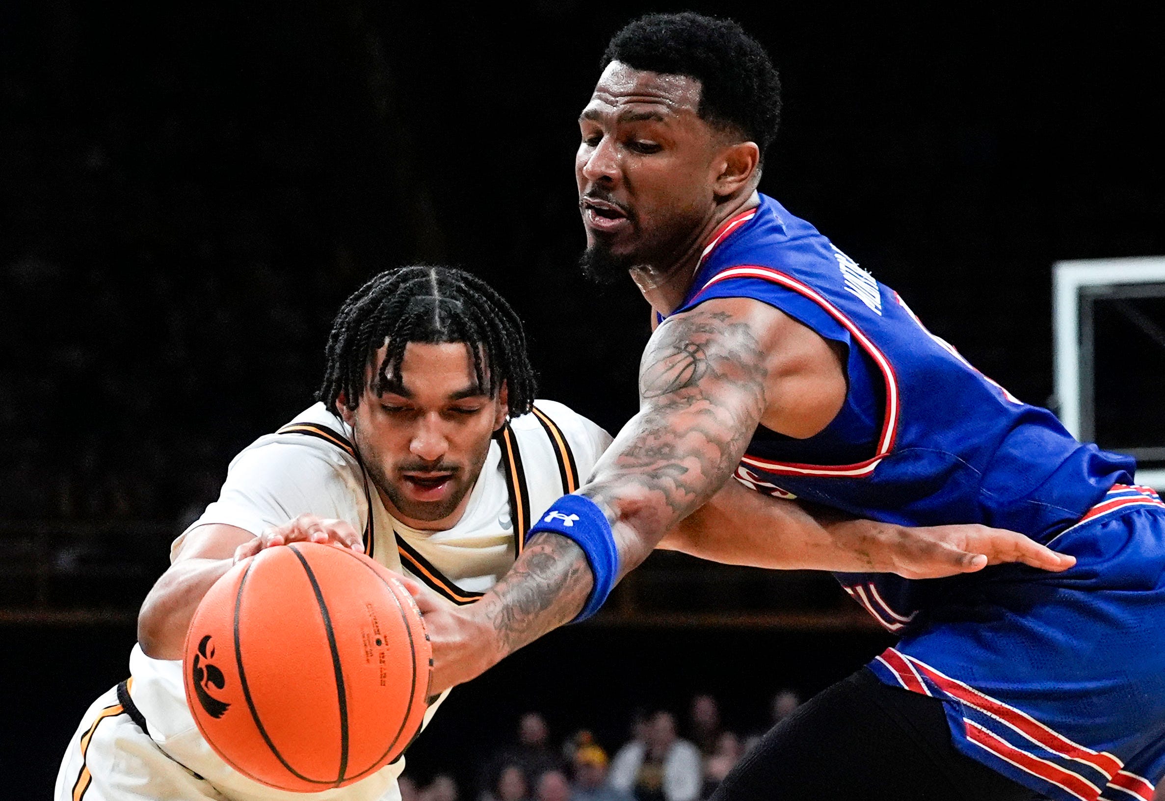 Iowa guard Kael Combs (11) and UMass Lowell guard Angel Montas Jr. (9) reach for the ball Dec. 29, 2025 at Carver-Hawkeye Arena in Iowa City, Iowa.