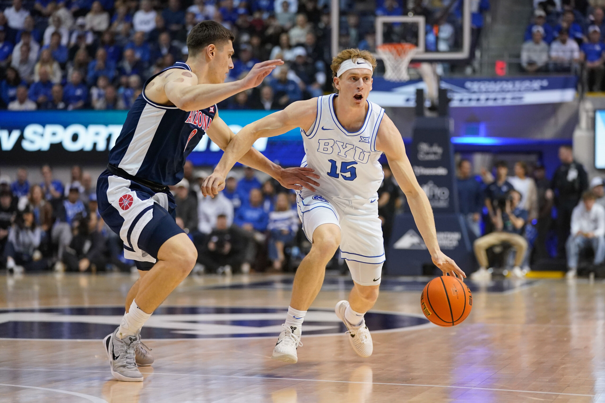 Jan 26, 2026; Provo, Utah, USA; BYU Cougars guard Richie Saunders (15) controls the ball while being defended by Arizona Wildcats forward Ivan Kharchenkov (8) during the first half at Marriott Center. Mandatory Credit: Aaron Baker-Imagn Images