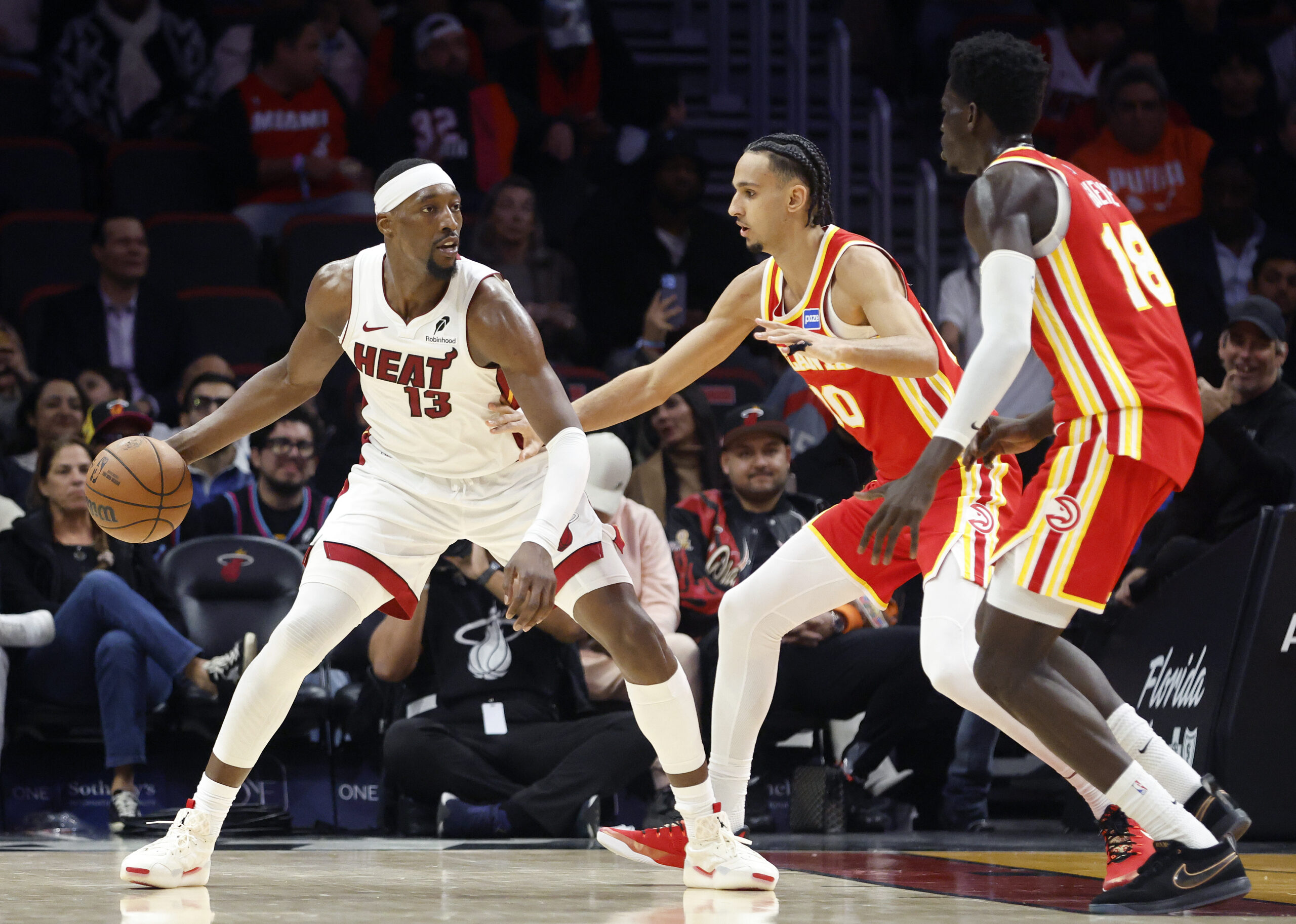 Feb 3, 2026; Miami, Florida, USA;  Atlanta Hawks forward Zaccharie Risacher (10) and forward Mouhamed Gueye (18) defend Miami Heat center Bam Adebayo (13) during the second half at Kaseya Center. Mandatory Credit: Rhona Wise-Imagn Images