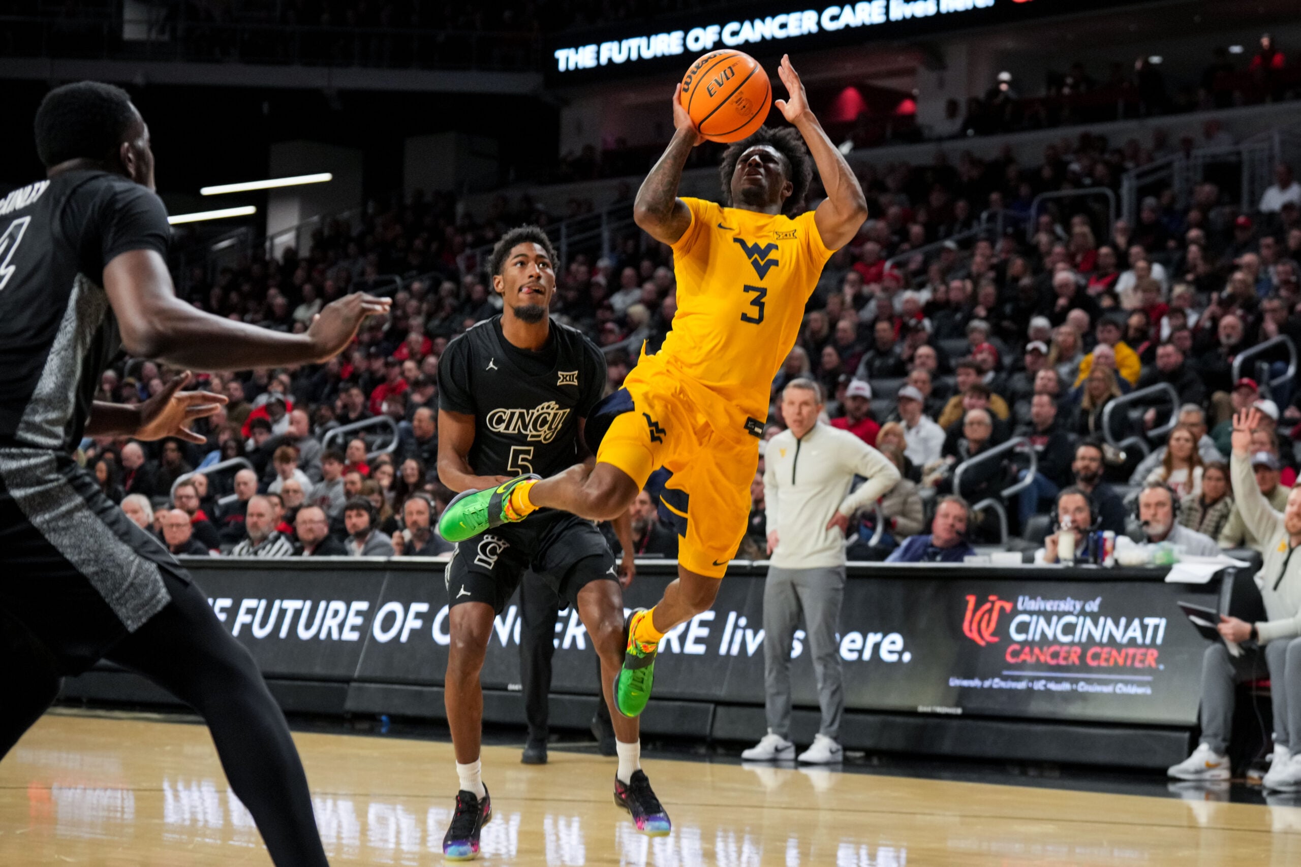 Feb 5, 2026; Cincinnati, Ohio, USA;  West Virginia Mountaineers guard Honor Huff (3) drives to the basket against Cincinnati Bearcats guard Sencire Harris (5) in the second half at Fifth Third Arena. Mandatory Credit: Aaron Doster-Imagn Images