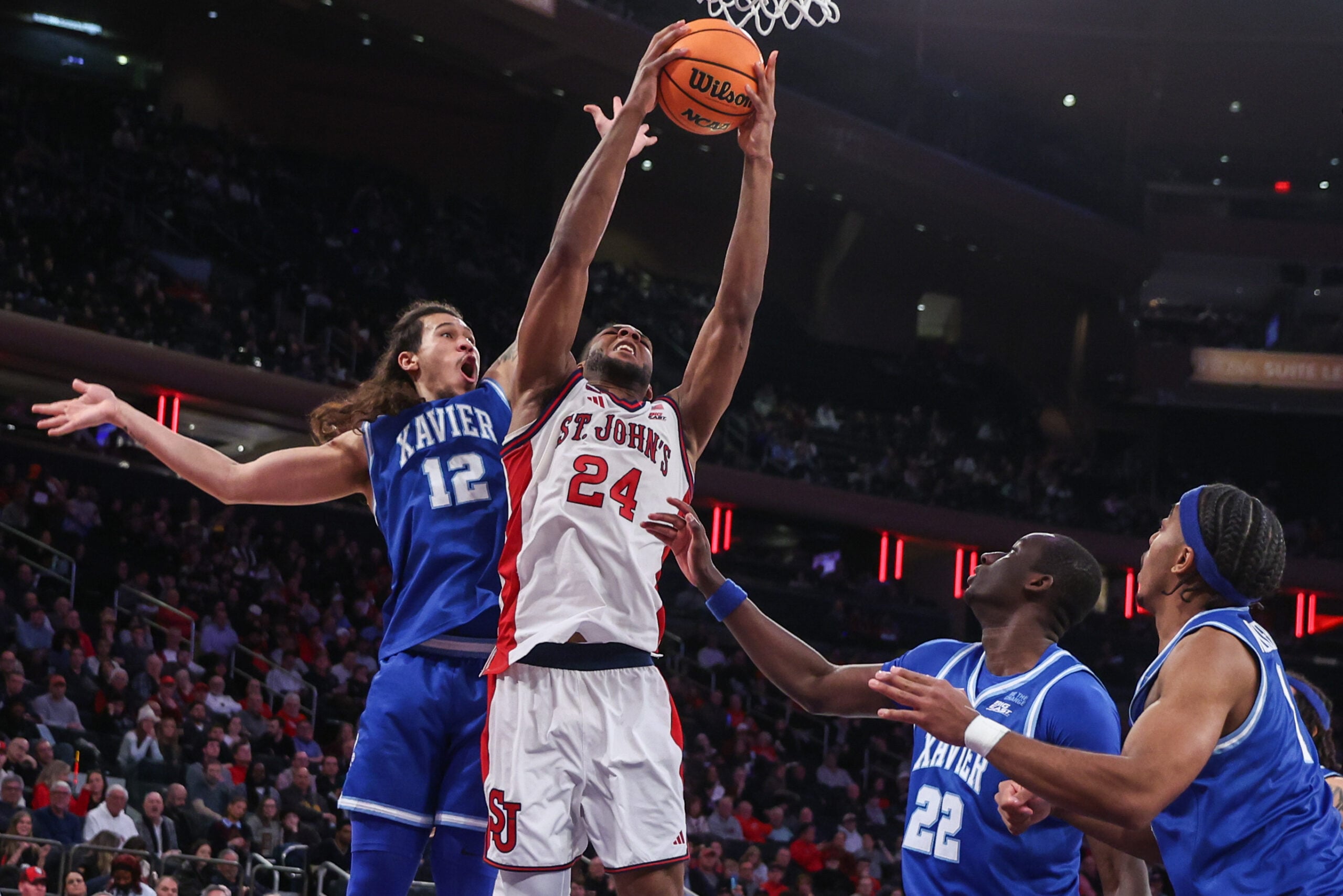 Feb 9, 2026; New York, New York, USA; St. John's Red Storm forward Zuby Ejiofor (24) grab a rebound away from Xavier Musketeers forward Tre Carroll (12) in the second half at Madison Square Garden Mandatory Credit: Wendell Cruz-Imagn Images