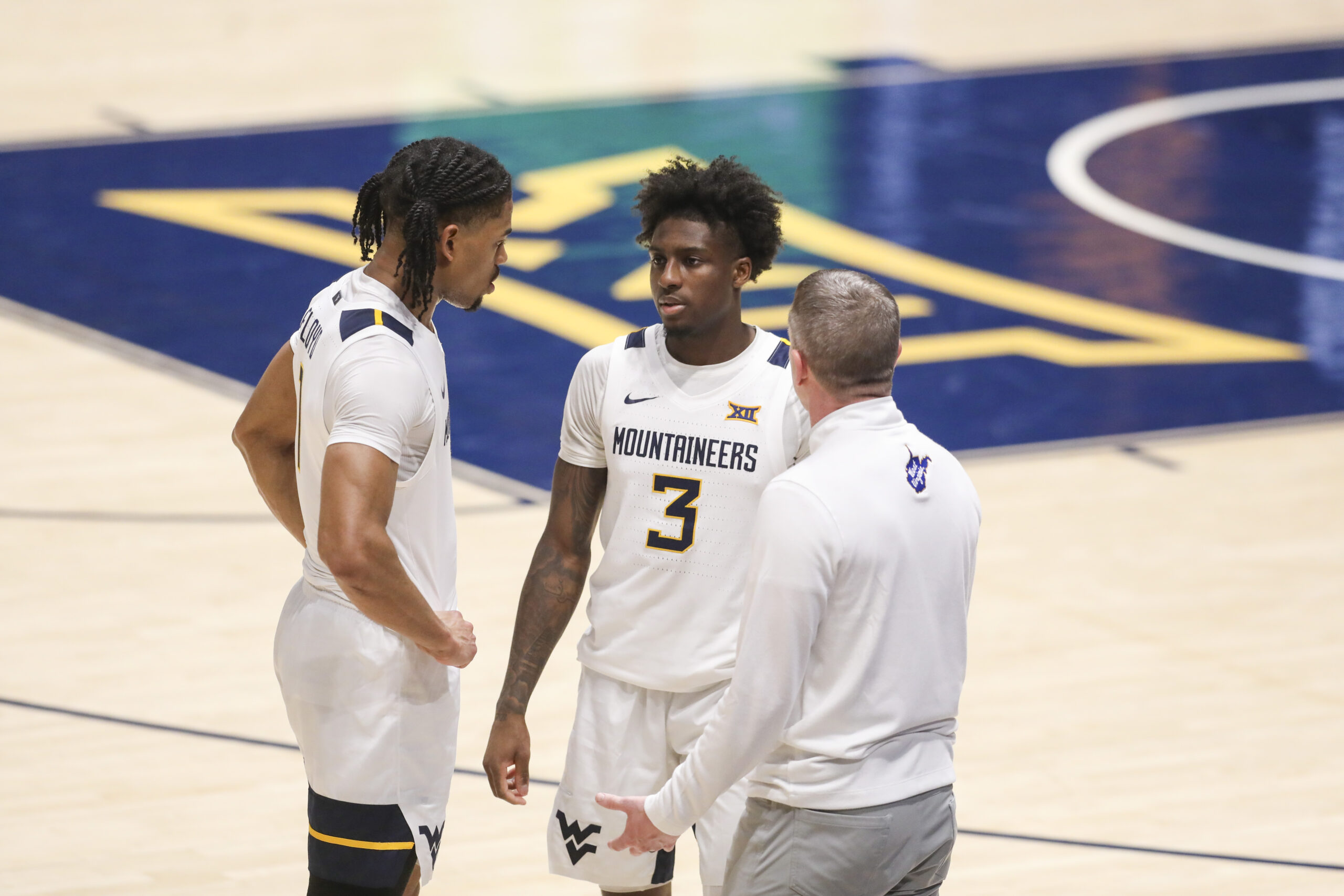 Feb 18, 2026; Morgantown, West Virginia, USA; West Virginia Mountaineers head coach Ross Hodge talks with guard Jasper Floyd (1) and guard Honor Huff (3) during the second half against the Utah Utes at Hope Coliseum. Mandatory Credit: Ben Queen-Imagn Images