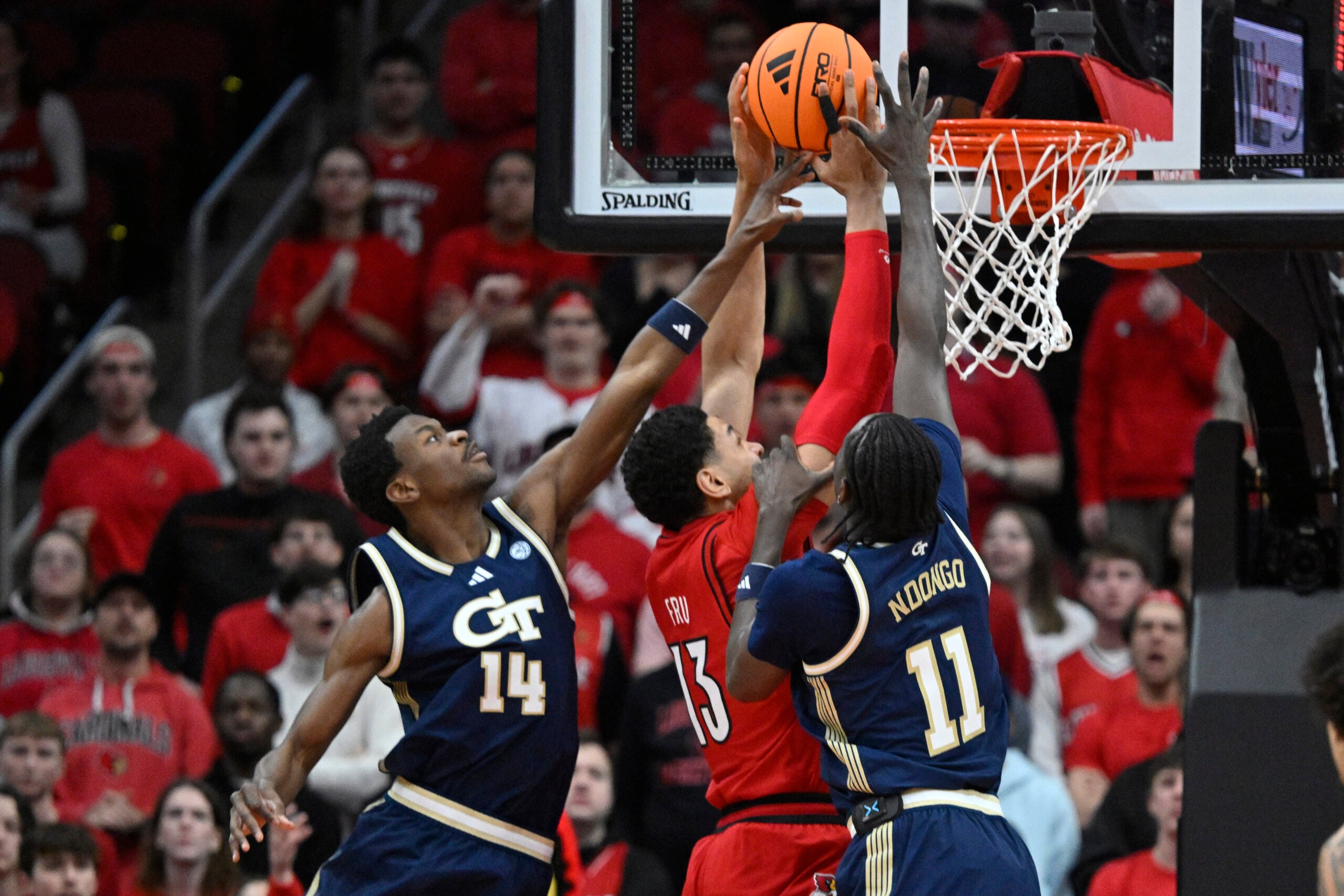 Feb 21, 2026; Louisville, Kentucky, USA;  Louisville Cardinals forward Sananda Fru (13) shoots against Georgia Tech Yellow Jackets forward Kowacie Reeves Jr. (14) and forward Baye Ndongo (11) during the first half at KFC Yum! Center. Mandatory Credit: Jamie Rhodes-Imagn Images