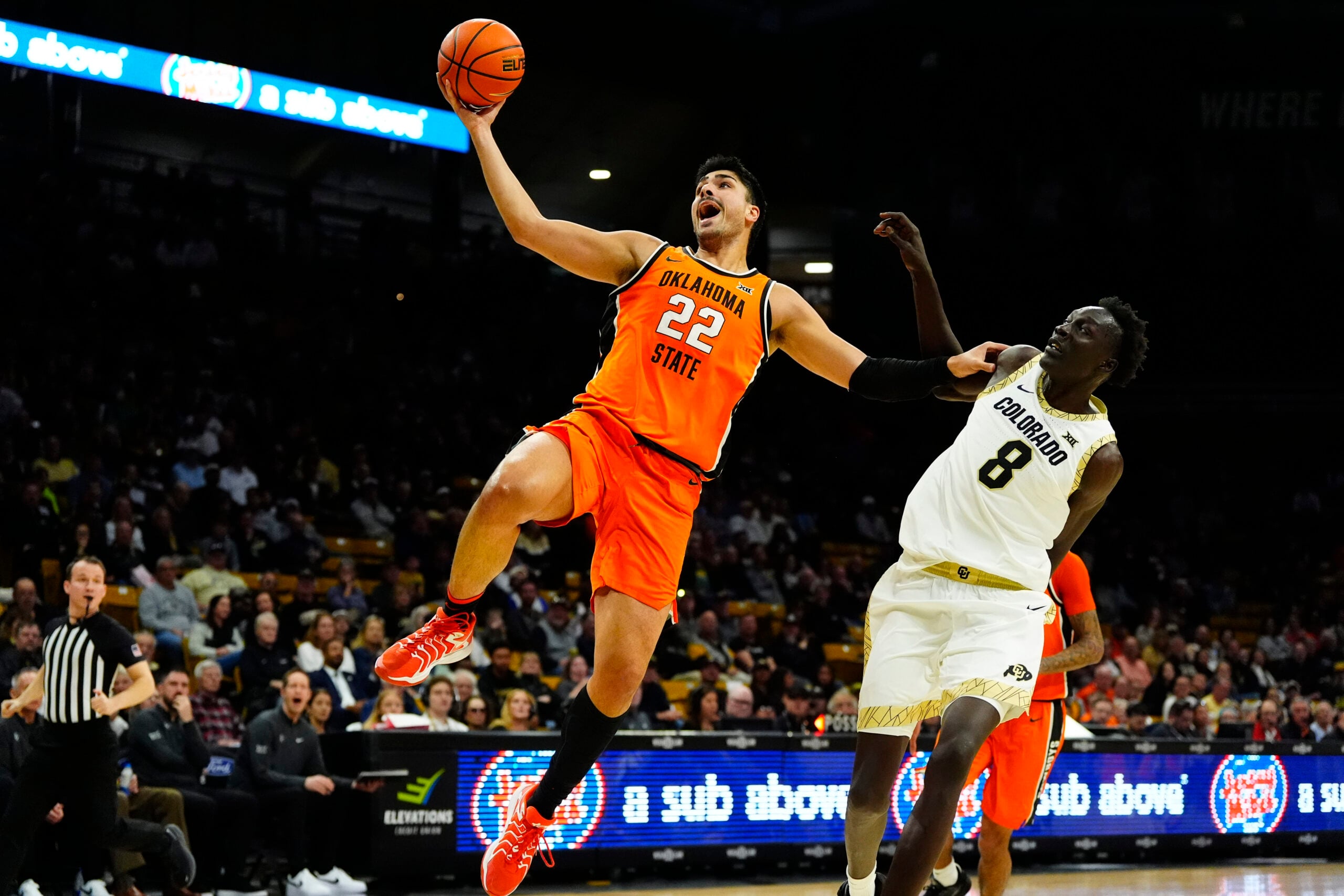 Feb 21, 2026; Boulder, Colorado, USA; Oklahoma State Cowboys center Parsa Fallah (22) finishes off a basket past Colorado Buffaloes forward Bangot Dak (8) in the first half at the CU Events Center. Mandatory Credit: Ron Chenoy-Imagn Images