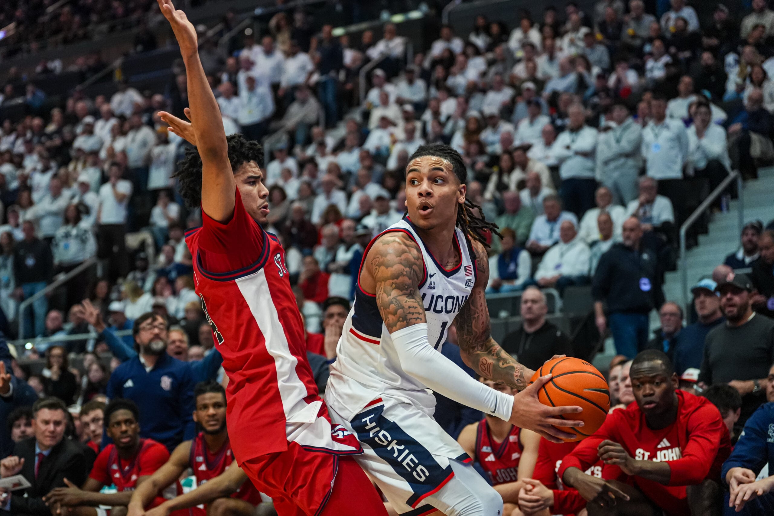 Feb 25, 2026; Hartford, Connecticut, USA; UConn Huskies guard Solo Ball (1) looks for an opening against St. John's Red Storm guard Oziyah Sellers (4) in the first half at PeoplesBank Arena. Mandatory Credit: David Butler II-Imagn Images