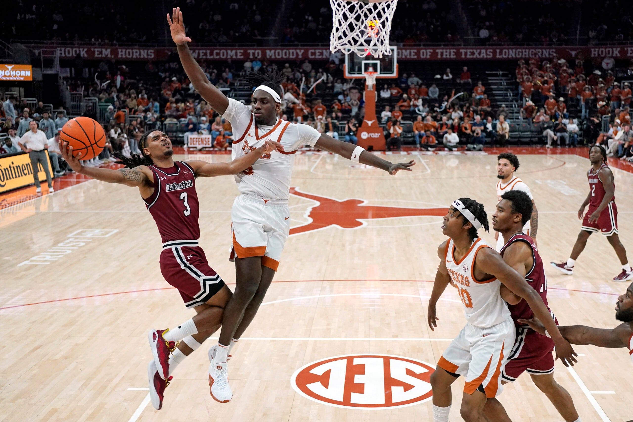 Dec 12, 2024; Austin, Texas, USA; New Mexico State Aggies guard Christian Cook (3) drives to the basket against Texas Longhorns forward Arthur Kaluma (6) during the first half at Moody Center. Mandatory Credit: Scott Wachter-Imagn Images