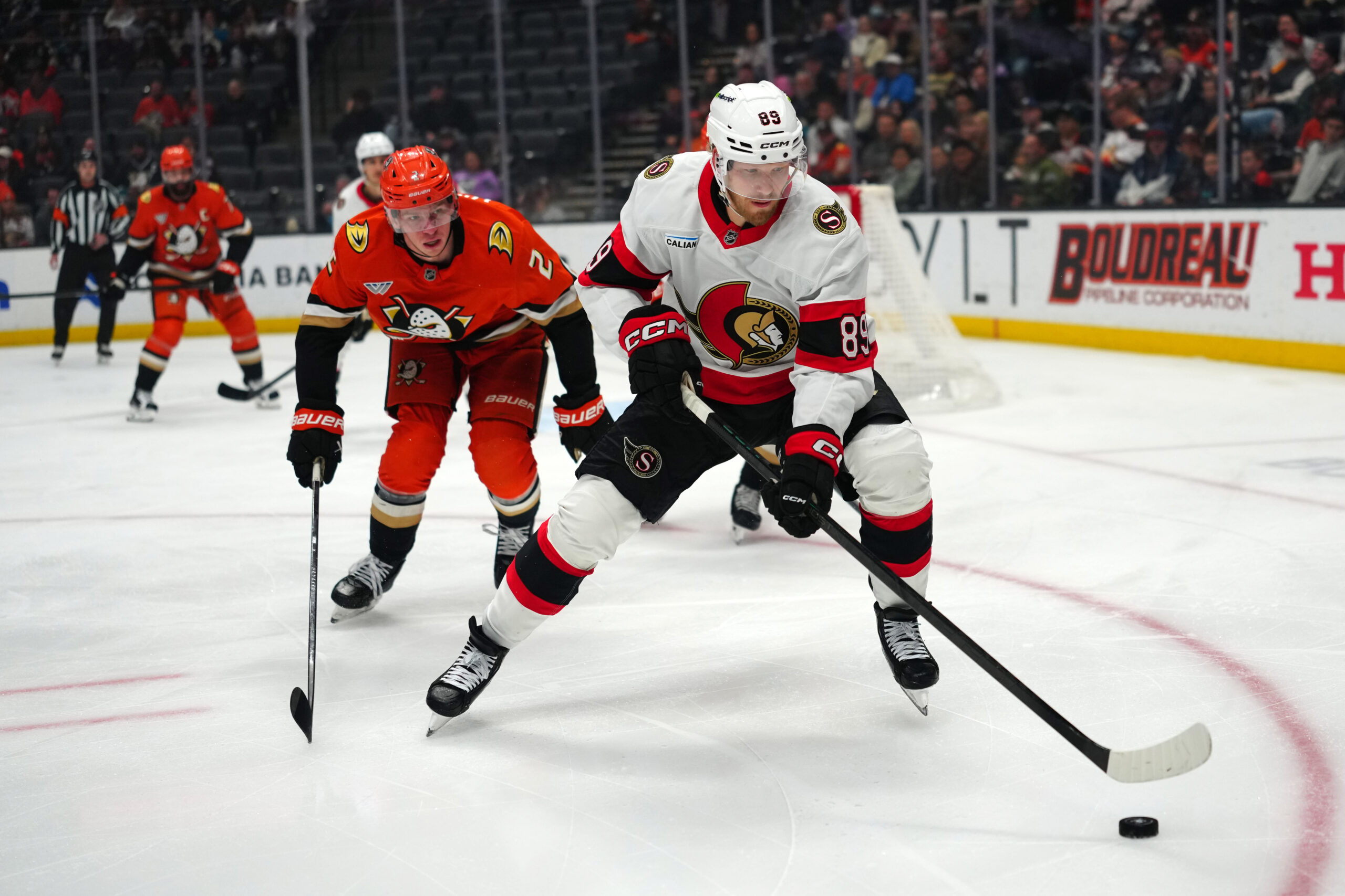 Nov 20, 2025; Anaheim, California, USA; Ottawa Senators center Lars Eller (89) and Anaheim Ducks defenseman Jackson Lacombe (2) battle for the puck in the first period at Honda Center. Mandatory Credit: Kirby Lee-Imagn Images