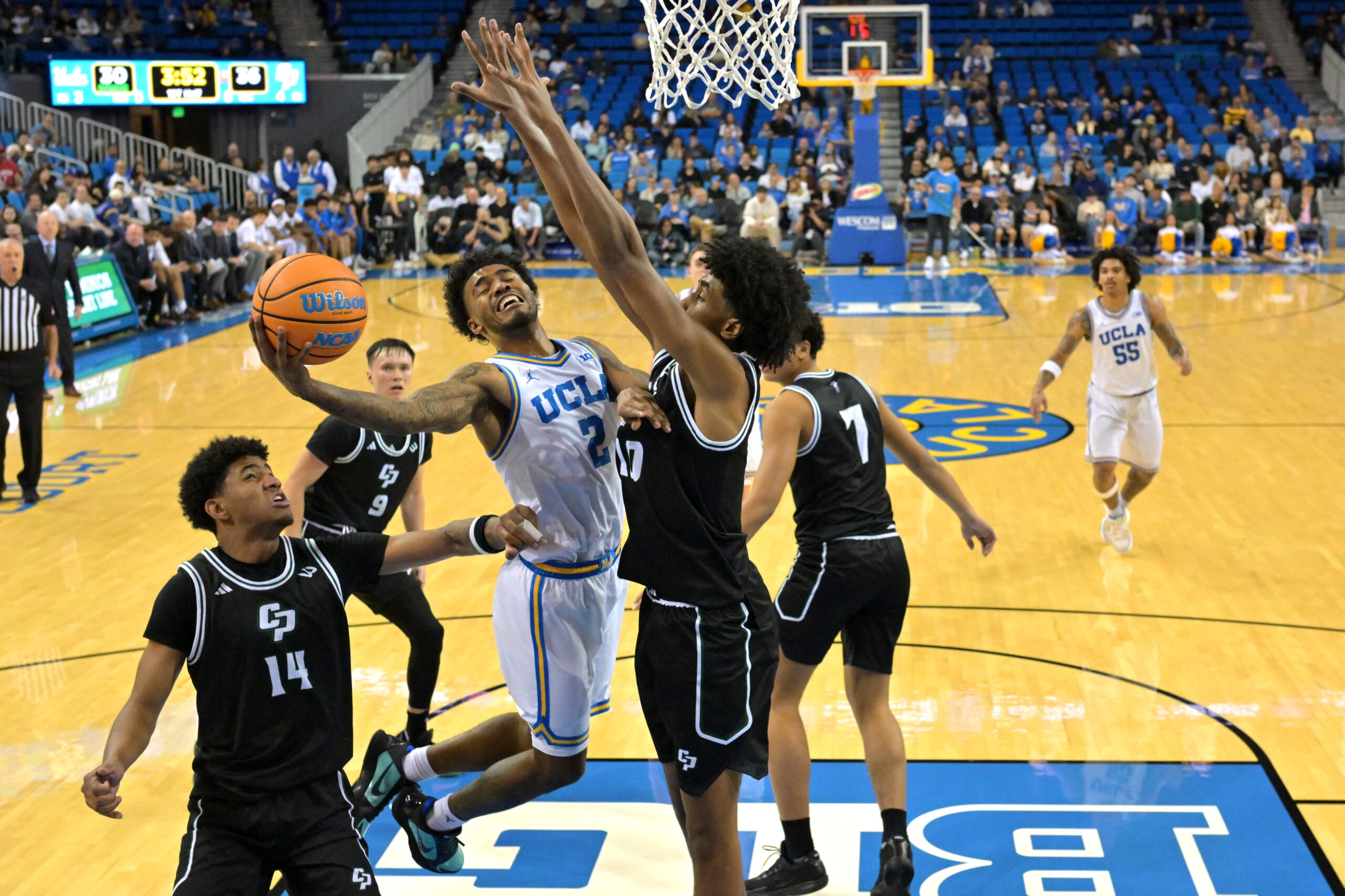 Dec 19, 2025; Los Angeles, California, USA; UCLA Bruins guard Donovan Dent (2) scores a basket over Cal Poly Mustangs guard Hamad Mousa (10) during the second half at Pauley Pavilion presented by Wescom Financial. Mandatory Credit: Jayne Kamin-Oncea-Imagn Images