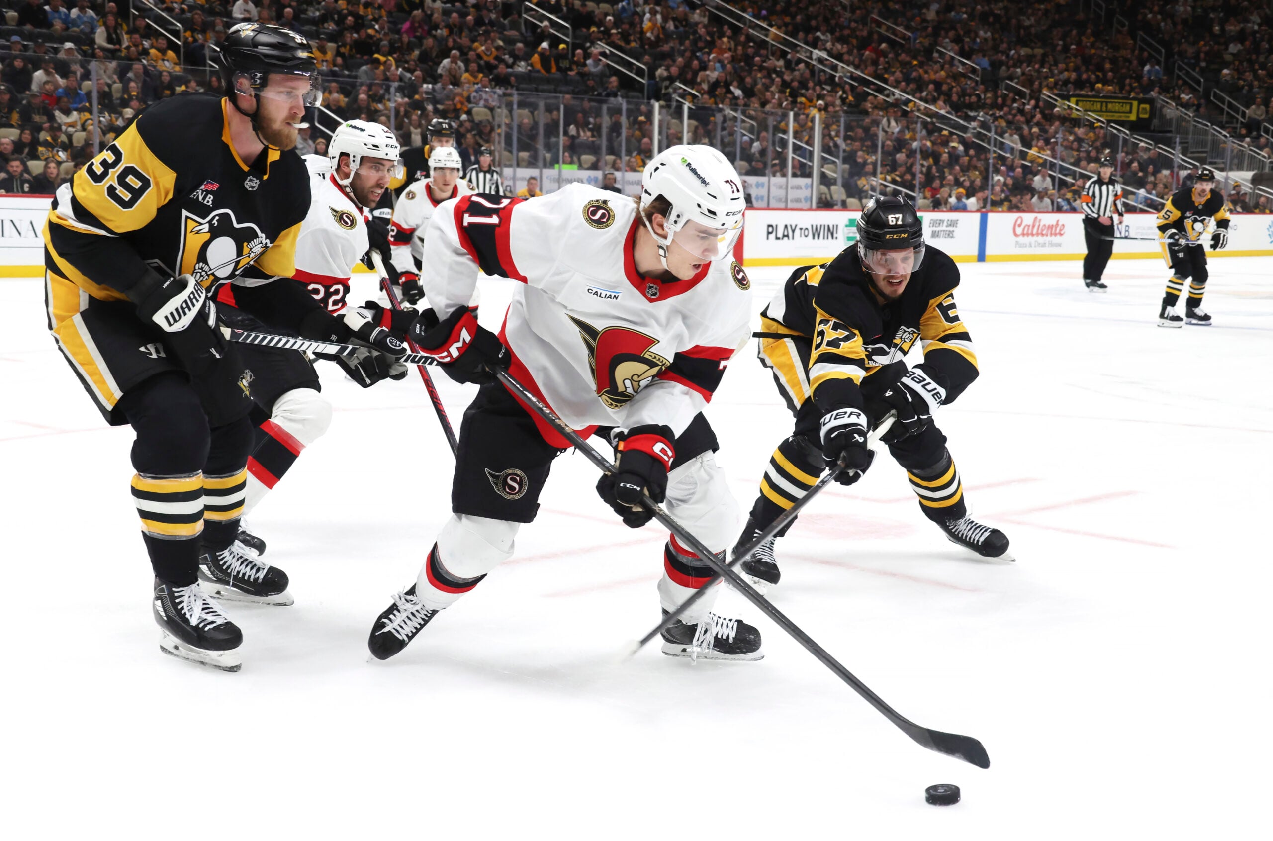 Feb 2, 2026; Pittsburgh, Pennsylvania, USA;  Ottawa Senators center Ridly Greig (71) clears the puck against Pittsburgh Penguins right wing Anthony Mantha (39) and right wing Rickard Rakell (67) during the third period at PPG Paints Arena. Mandatory Credit: Charles LeClaire-Imagn Images