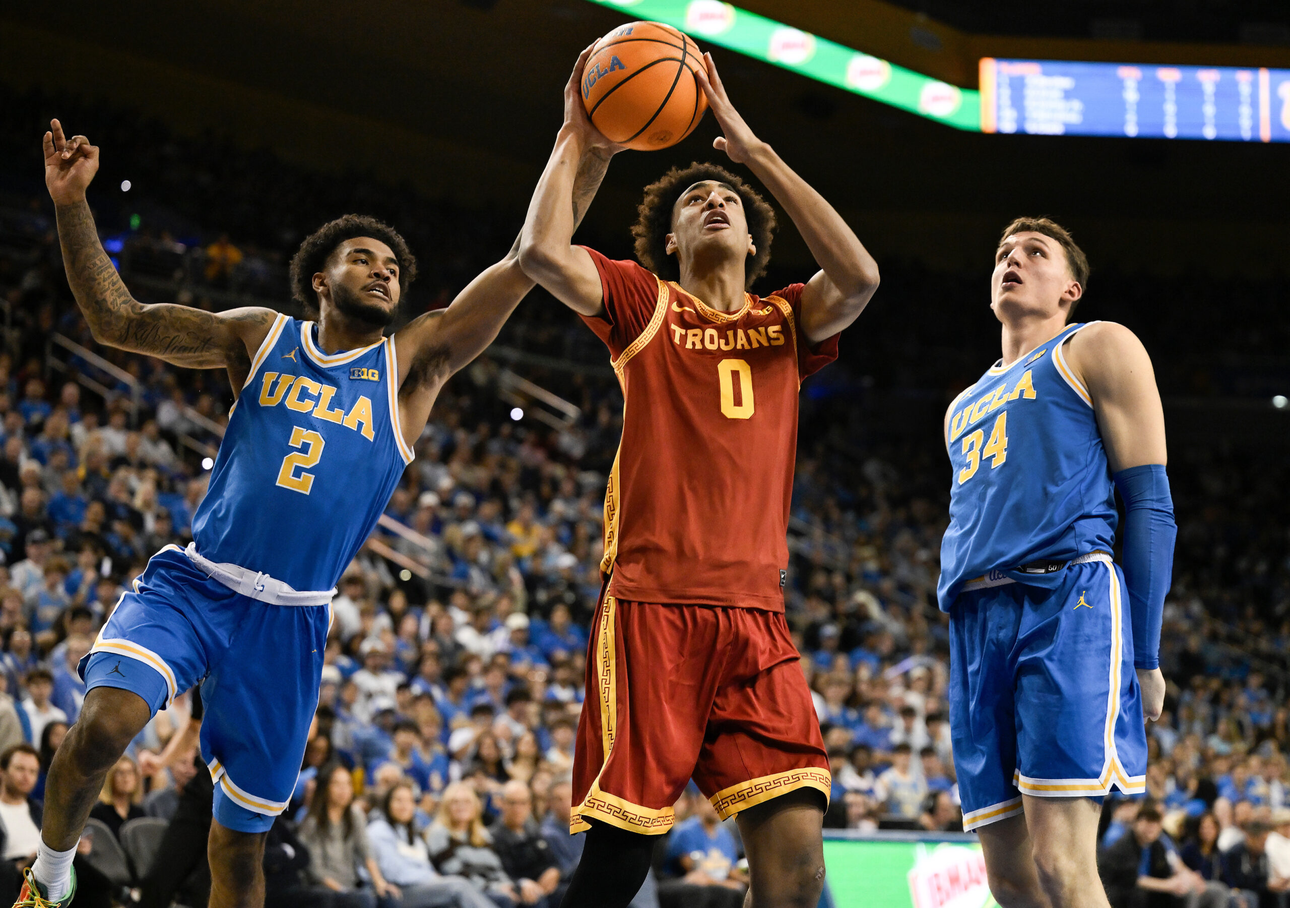Feb 24, 2026; Los Angeles, California, USA; Southern California Trojans guard Alijah Arenas (0) drives to the basket past UCLA Bruins guard Donovan Dent (2) and forward Tyler Bilodeau (34) during the first half at Pauley Pavilion presented by Wescom Financial. Mandatory Credit: Robert Hanashiro-Imagn Images