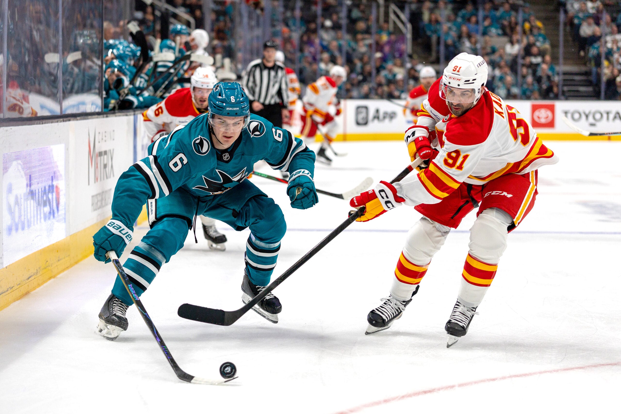 Feb 26, 2026; San Jose, California, USA; San Jose Sharks defenseman Sam Dickinson (6) and Calgary Flames center Nazem Kadri (91) fight for the puck during the first period at SAP Center at San Jose. Mandatory Credit: Bob Kupbens-Imagn Images