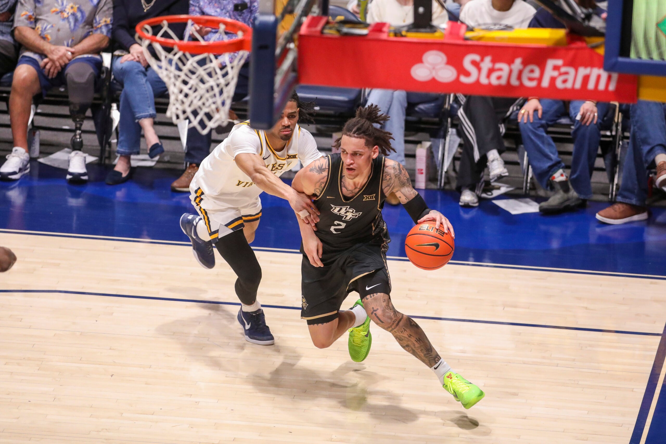 Mar 6, 2026; Morgantown, West Virginia, USA; UCF Knights guard Riley Kugel (2) dribbles along the baseline past West Virginia Mountaineers guard Jasper Floyd (1) during the first half at Hope Coliseum. Mandatory Credit: Ben Queen-Imagn Images