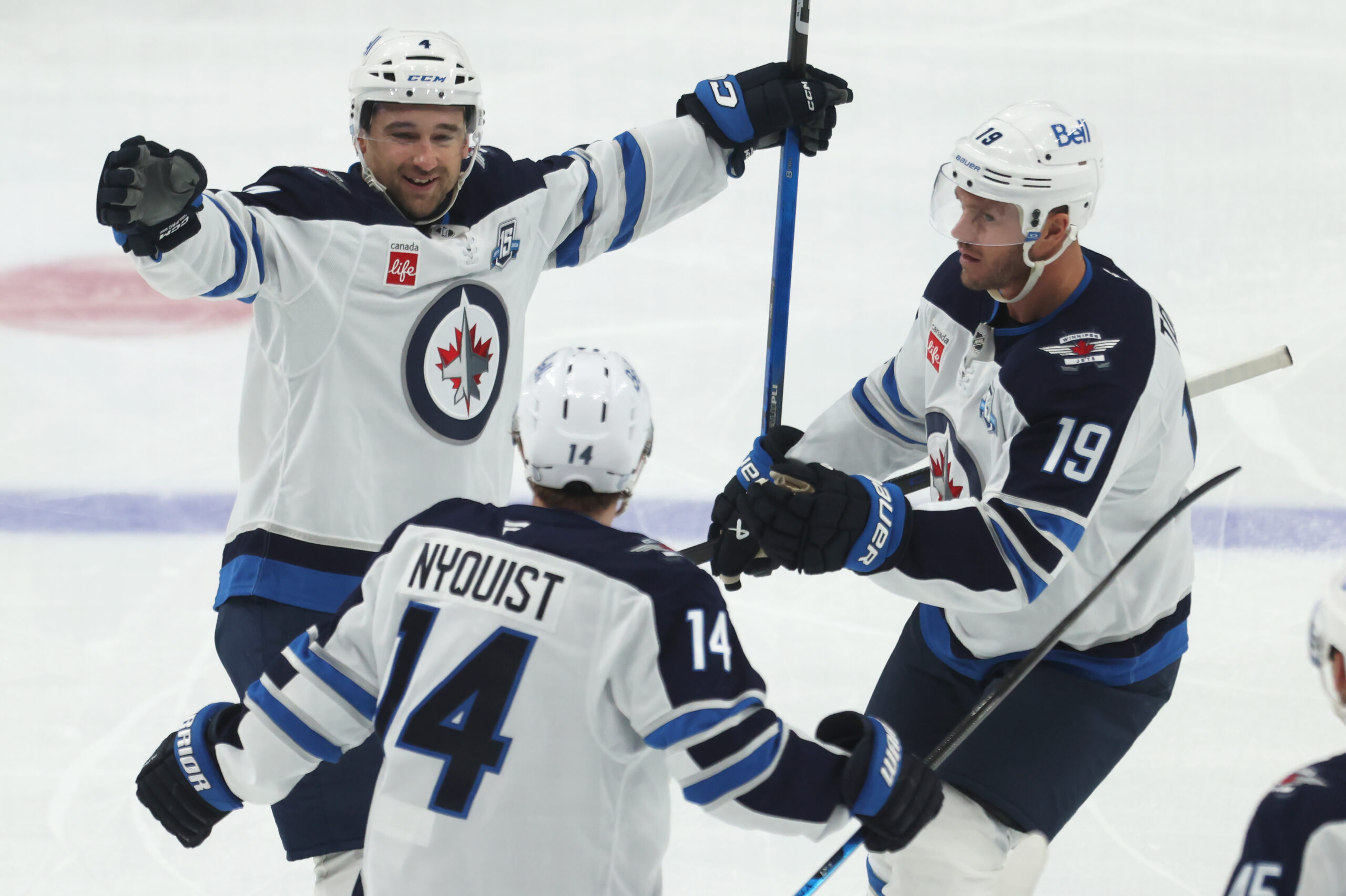 Mar 21, 2026; Pittsburgh, Pennsylvania, USA;  Winnipeg Jets defenseman Neal Pionk (4) celebrates after scoring a goal with right wing Gustav Nyquist (14) and center Jonathan Toews (19) against the Pittsburgh Penguins during the third period at PPG Paints Arena. Mandatory Credit: Charles LeClaire-Imagn Images