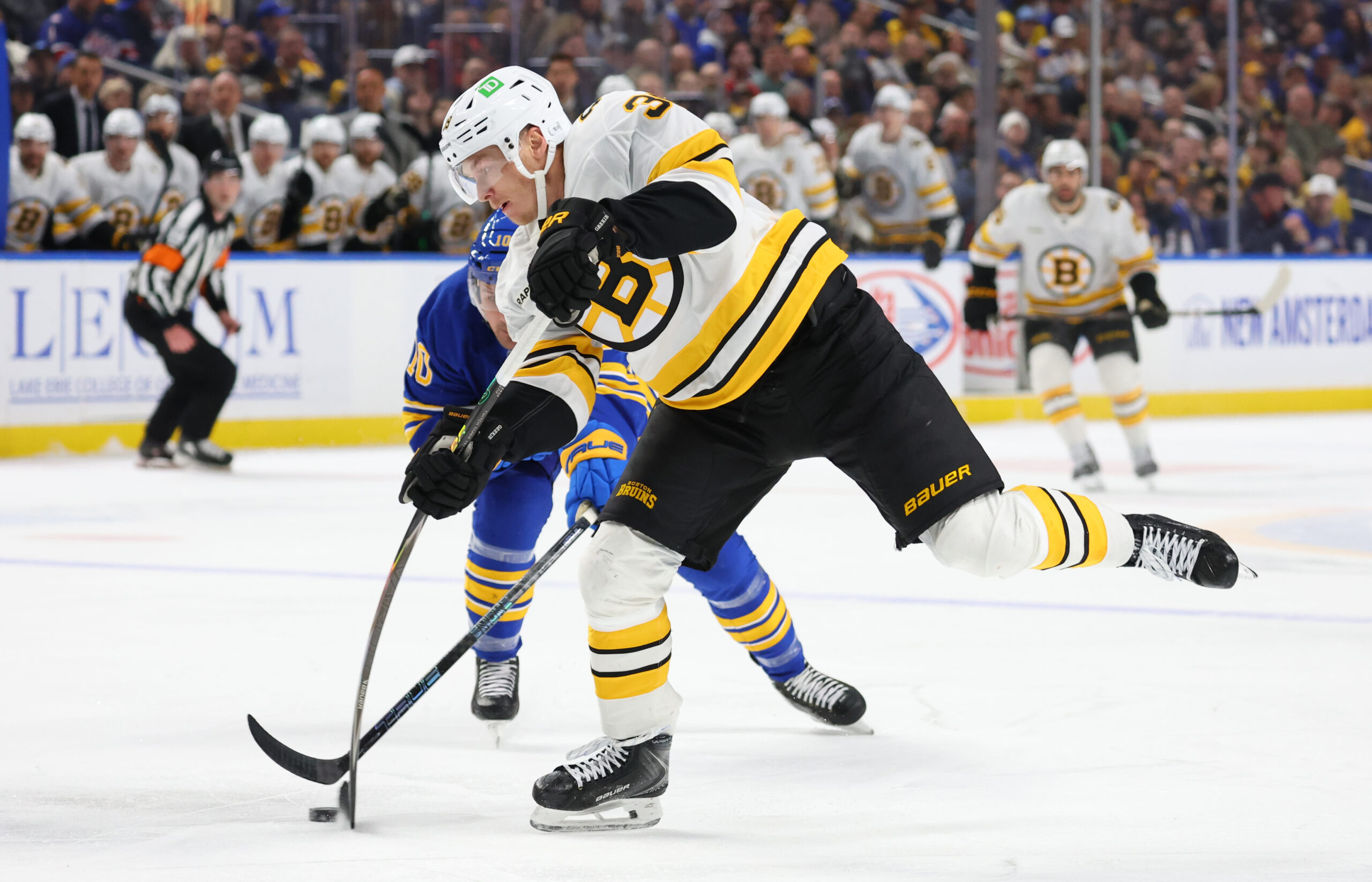 Mar 25, 2026; Buffalo, New York, USA;  Buffalo Sabres center Sam Carrick (10) tries to block a shot by Boston Bruins center Morgan Geekie (39) during the first period at KeyBank Center. Mandatory Credit: Timothy T. Ludwig-Imagn Images