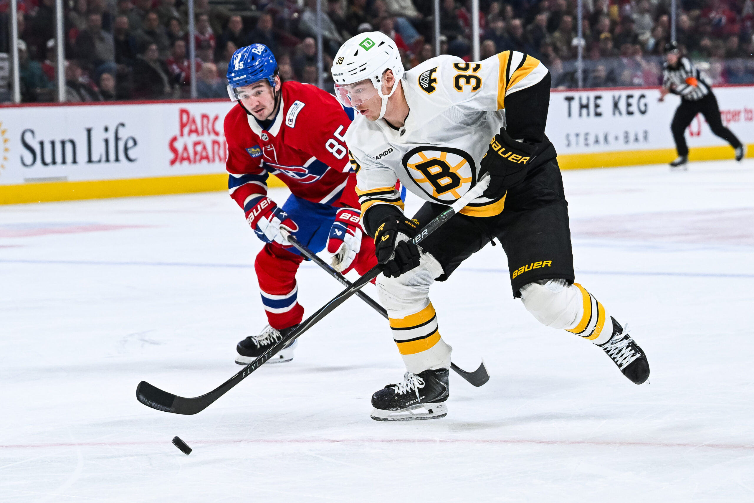 Mar 17, 2026; Montreal, Quebec, CAN; Boston Bruins center Morgan Geekie (39) plays the puck against Montreal Canadiens left wing Alexandre Texier (85) during the third period at Bell Centre. Mandatory Credit: David Kirouac-Imagn Images