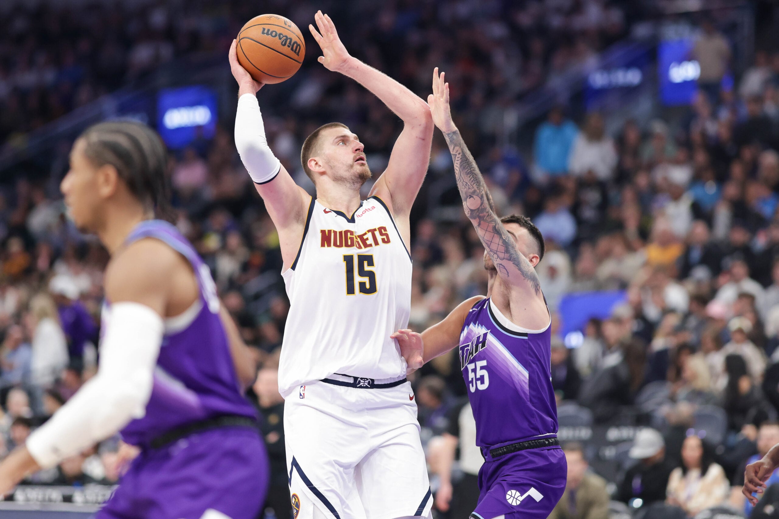Apr 1, 2026; Salt Lake City, Utah, USA;  Denver Nuggets center Nikola Jokić (15) shoots the ball over Utah Jazz guard John Konchar (55) during the second half at Delta Center. Mandatory Credit: Chris Nicoll-Imagn Images