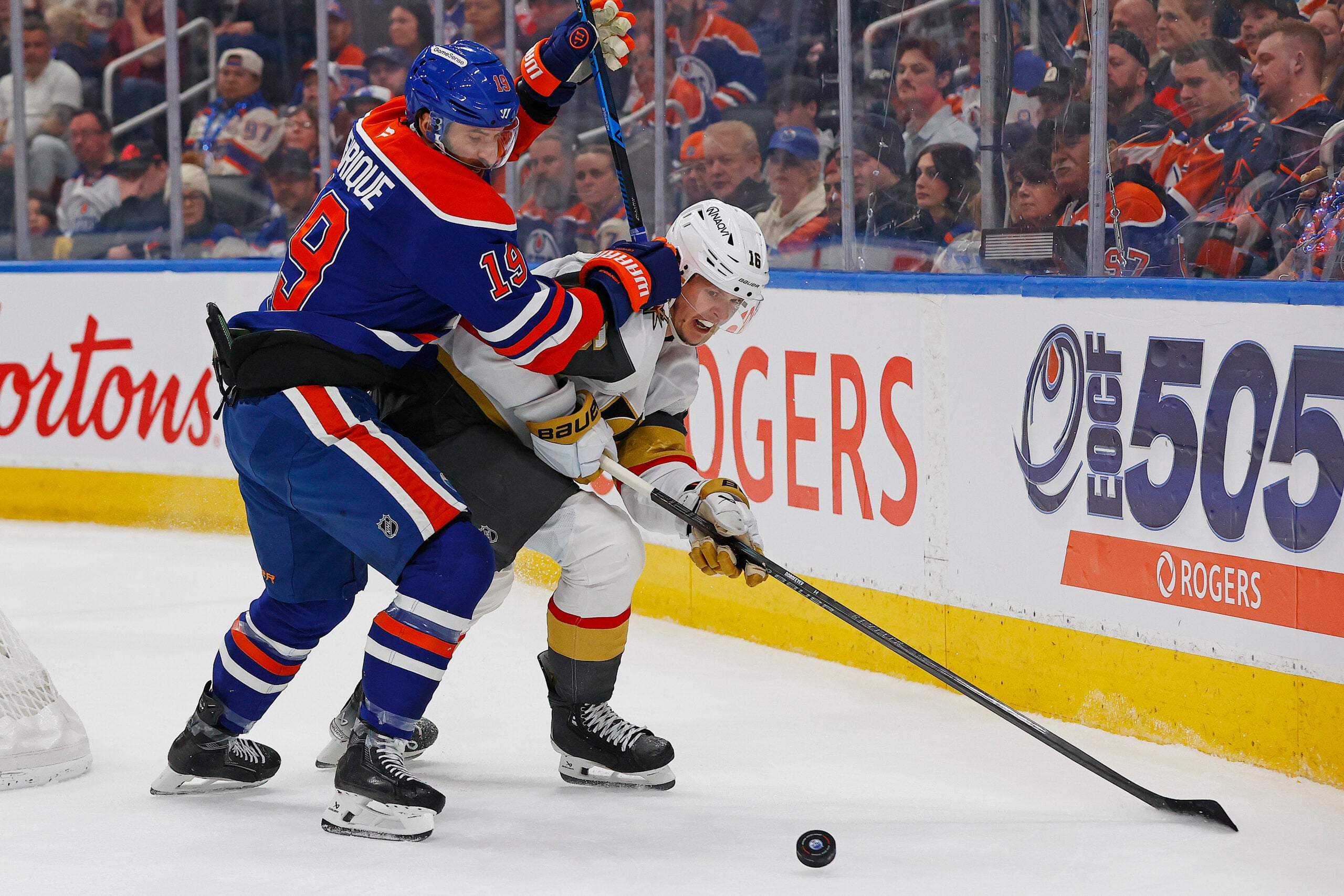 Apr 4, 2026; Edmonton, Alberta, CAN; Edmonton Oilers forward Adam Henrique (19) and Vegas Golden Knights forward Pavel Dorofeyev (16) battle along the boards for a loose puck during the second period at Rogers Place. Mandatory Credit: Perry Nelson-Imagn Images