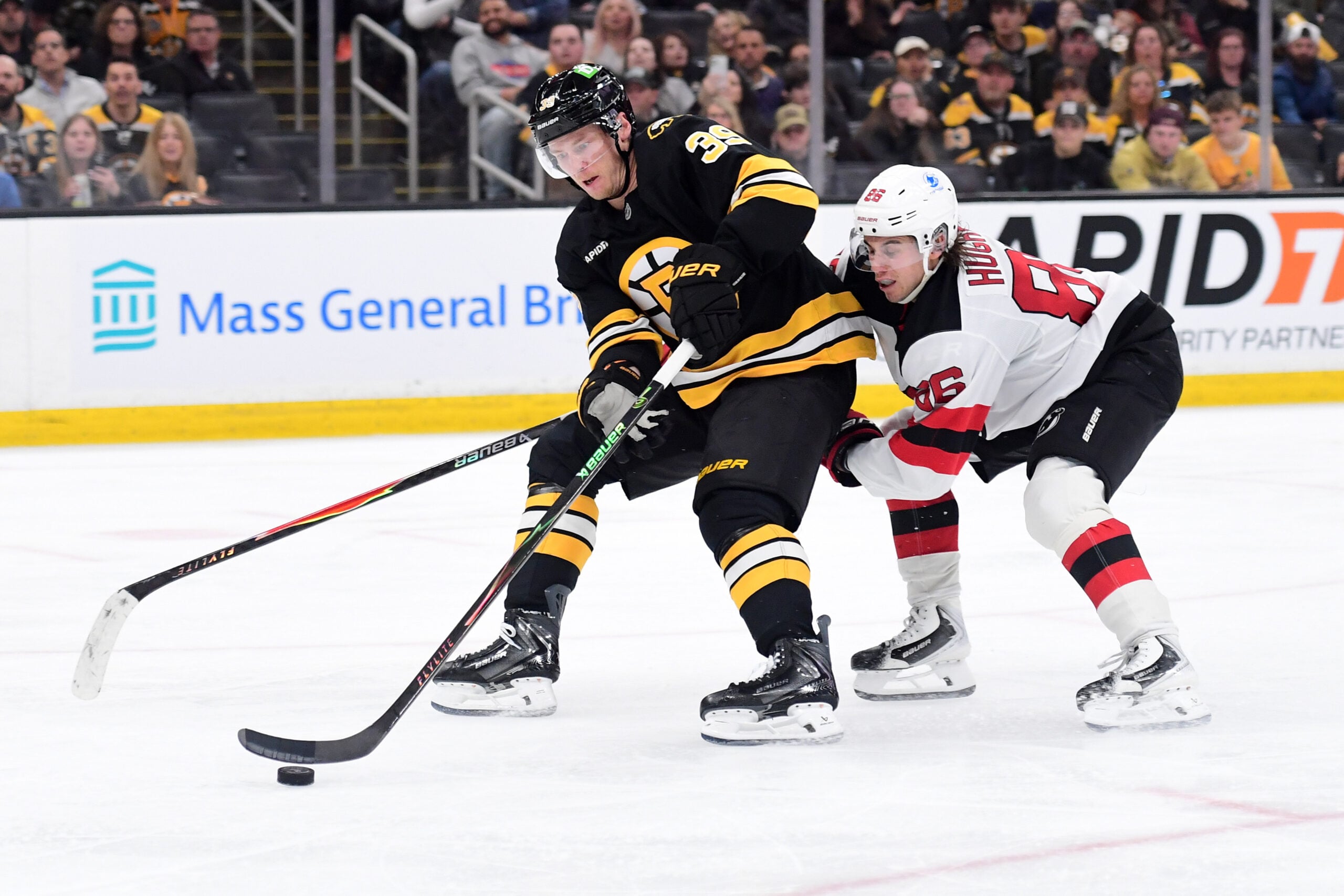 Apr 14, 2026; Boston, Massachusetts, USA; Boston Bruins center Morgan Geekie (39) controls the puck against New Jersey Devils center Jack Hughes (86) during the third period at TD Garden. Mandatory Credit: Bob DeChiara-Imagn Images